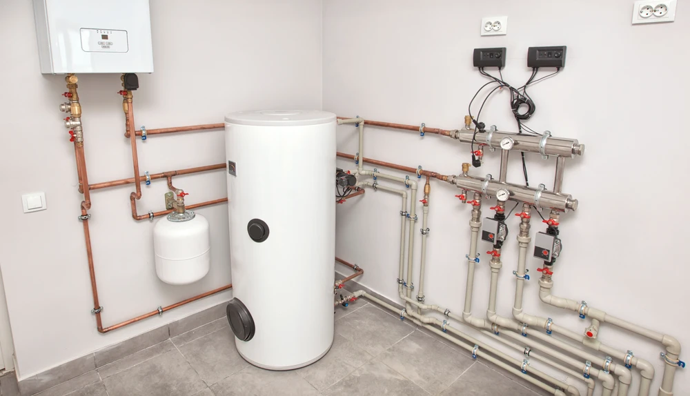 Local technique moderne avec chaudière murale blanche, ballon de stockage cylindrique et réseau de distribution complexe