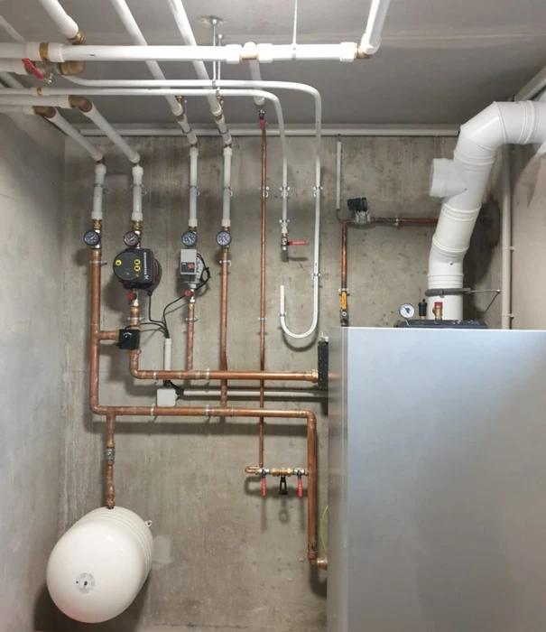 Un technicien planant sur un toit en tuiles rouges lève un panneau solaire qu'il est sur le point d'ajouter à un système photovoltaïque en cours d'installation