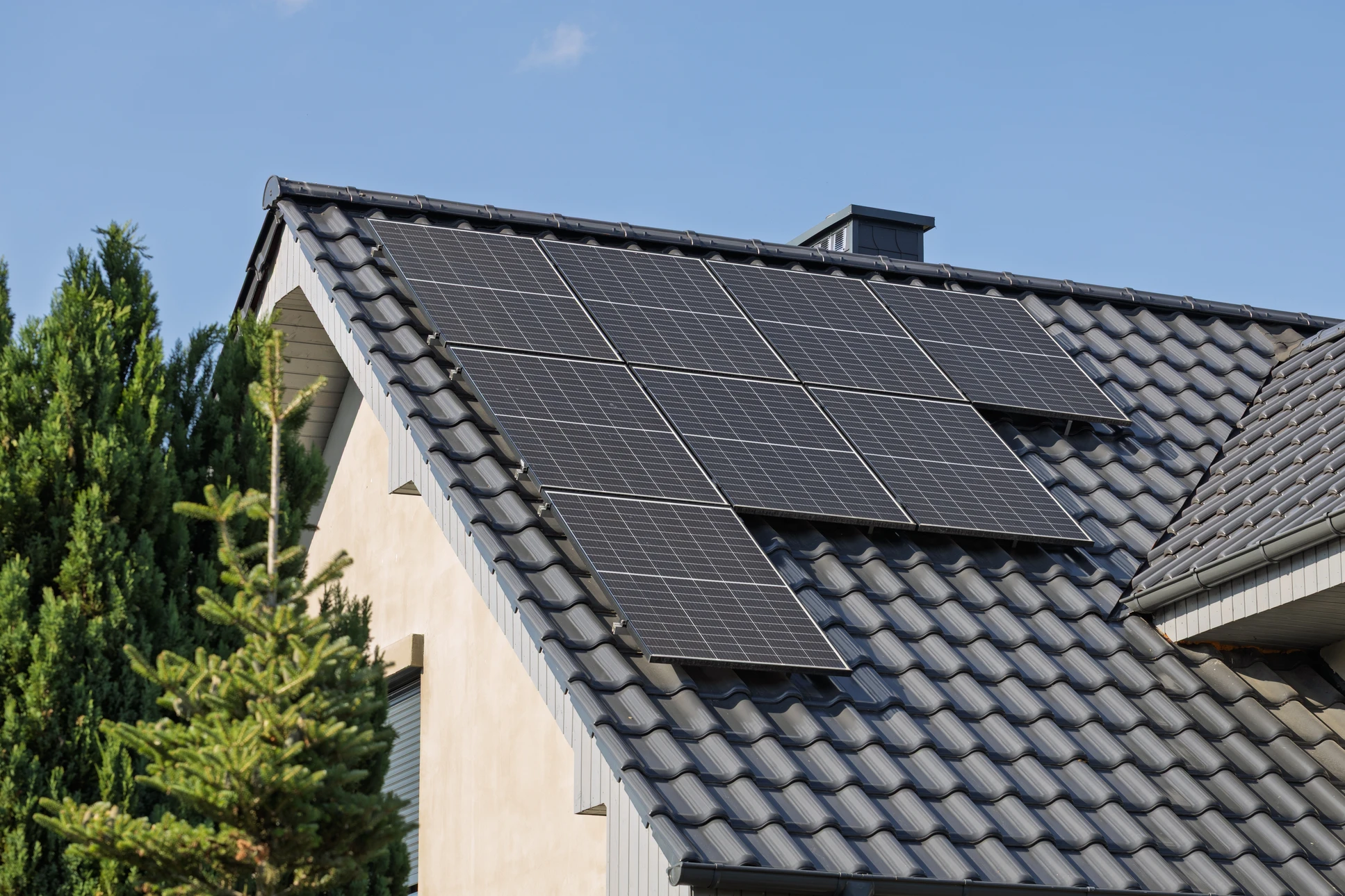 Ouvrier en équipement de sécurité installant des tuiles solaires photovoltaïques sur toiture résidentielle par temps ensoleillé