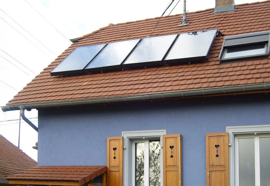 Technicien en combinaison verte installant ou entretenant des panneaux solaires photovoltaïques sur toiture, portant gants de protection, utilisant outil de serrage sur système de fixation