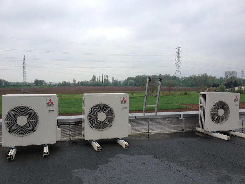Extérieur résidentiel moderne avec pompe à chaleur air-eau installée contre mur blanc