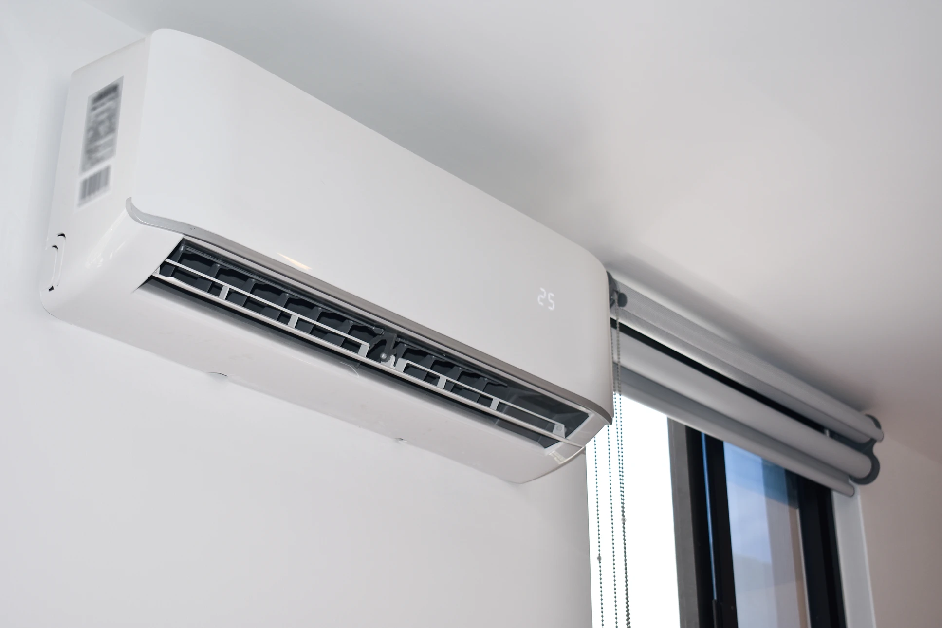 Technicien en combinaison de travail installant une unité de climatisation murale dans un intérieur résidentiel moderne